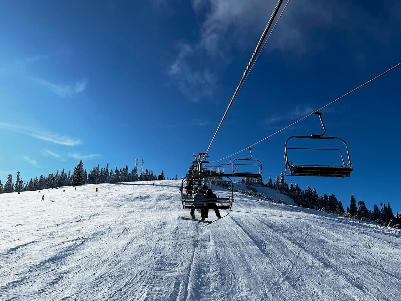 Looking uphill at a ski chairlift under a bright blue sky