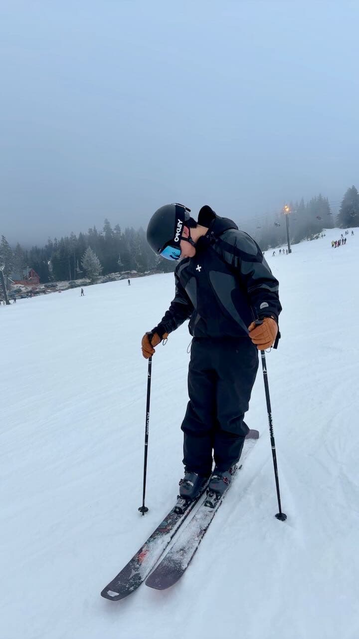 A skier standing on a snowy slope in foggy weather