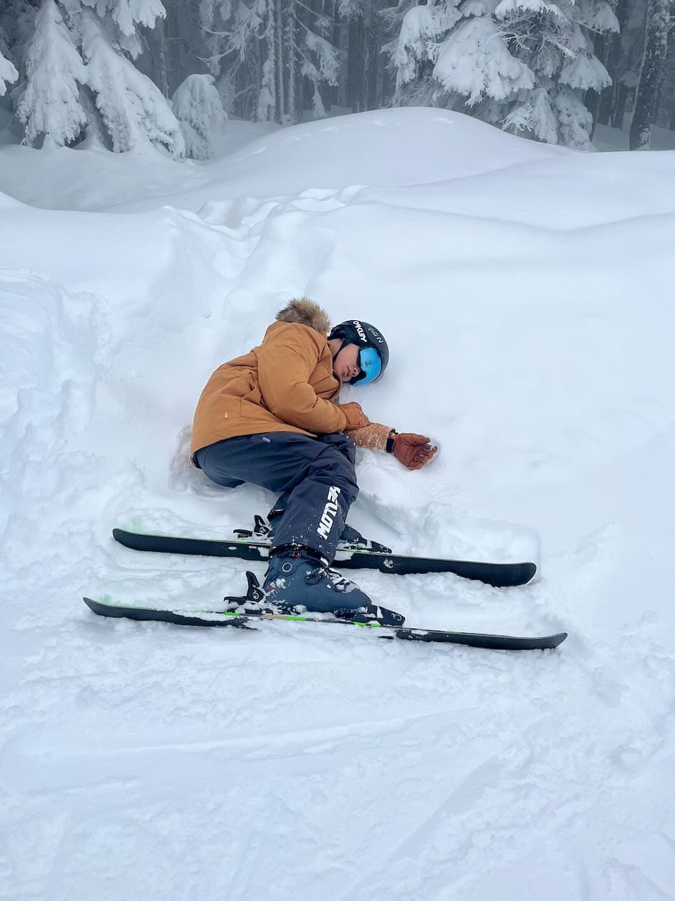 A skier taking a playful break in deep snow